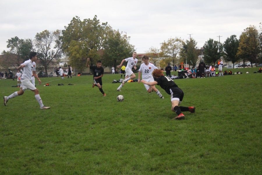 Freshman Jacob Grodsky retrieves the ball while freshman Caleb Johnson slips sprinting toward the same ball.